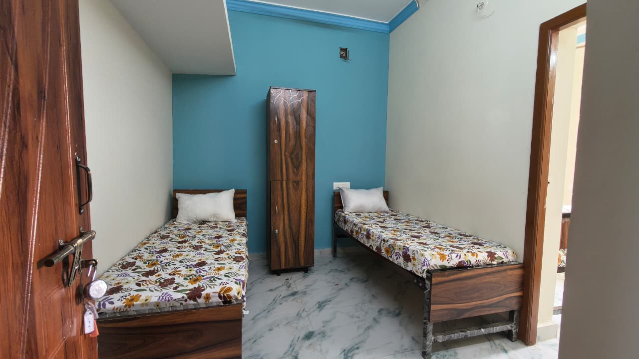 Double sharing room seen from the door, with a bed either side of the wardrobe and a blue accent wall