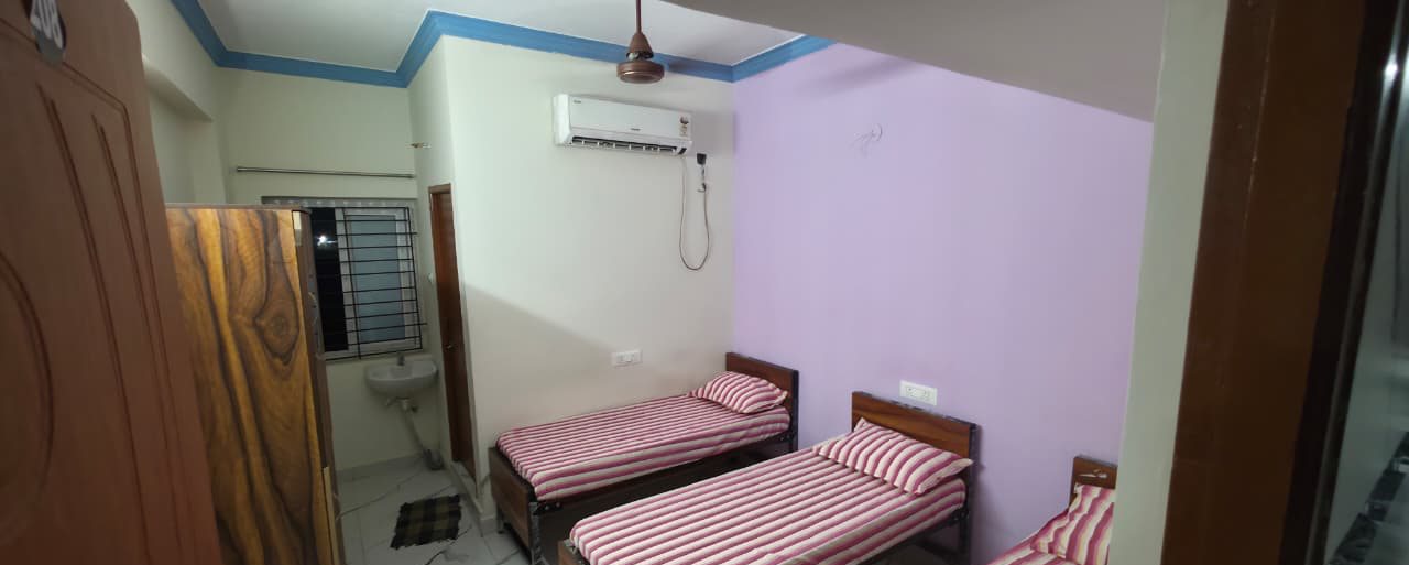 Triple sharing room with an air conditioner, ceiling fan, washbasin and attached bathroom door